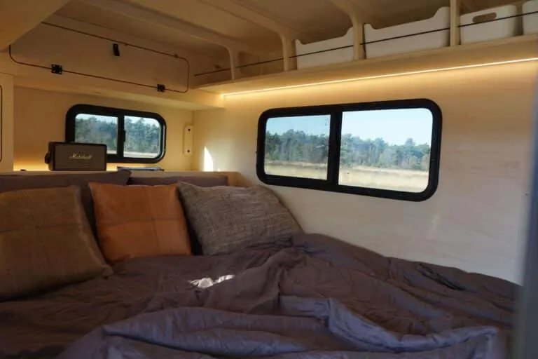 Het bed in de minicaravan met uitzicht door het zijraam