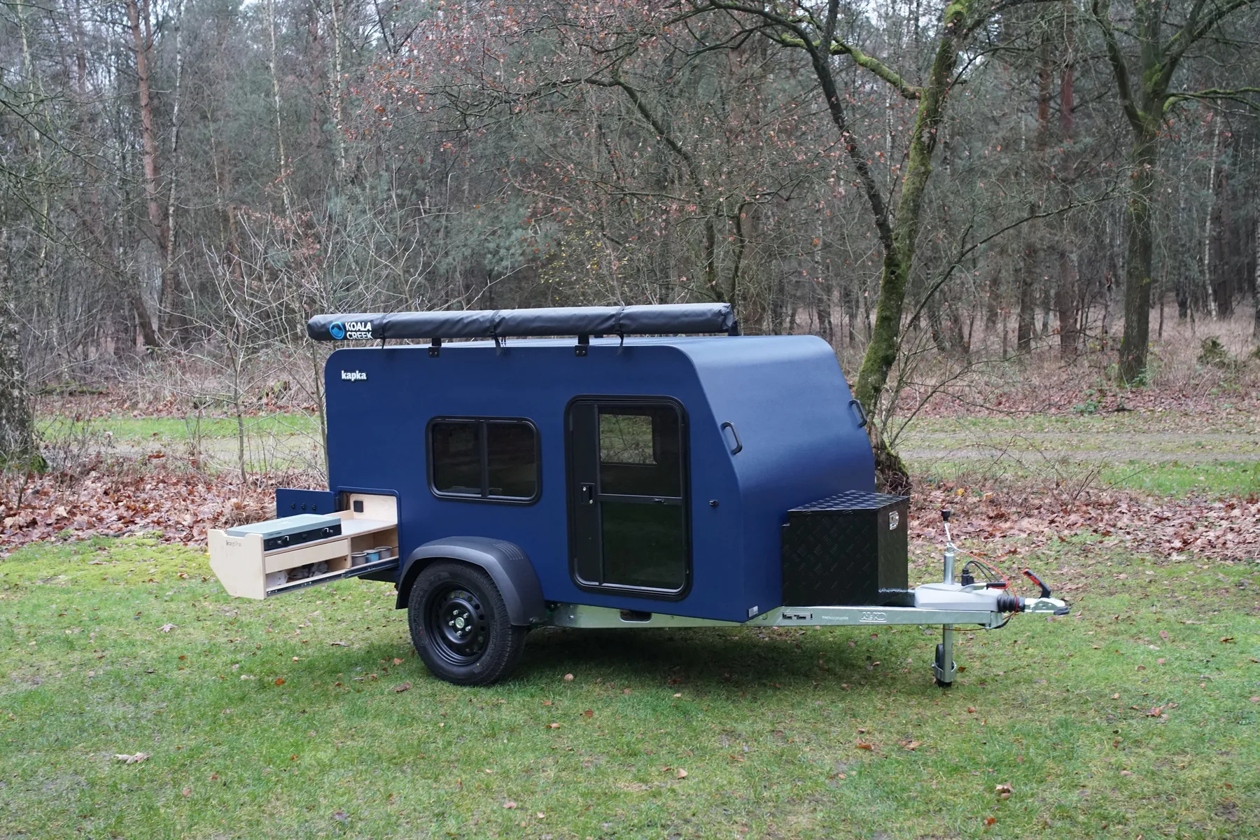 De blauwe Marco Polo in het bos, met de keuken uitgeschoven